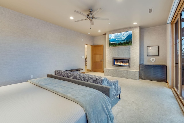 carpeted bedroom featuring ceiling fan and a large fireplace