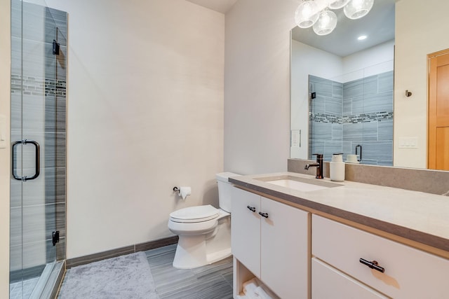 bathroom with a shower with door, vanity, and toilet