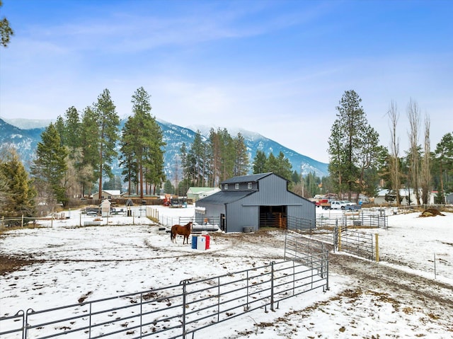 snowy yard featuring a mountain view, a rural view, and an outdoor structure