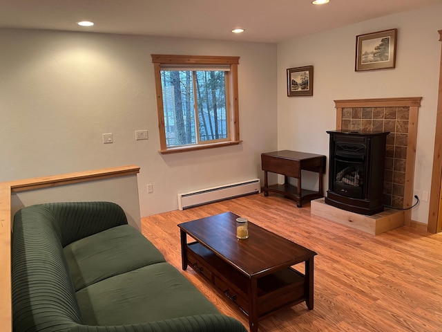 living room with hardwood / wood-style flooring, a wood stove, and a baseboard radiator