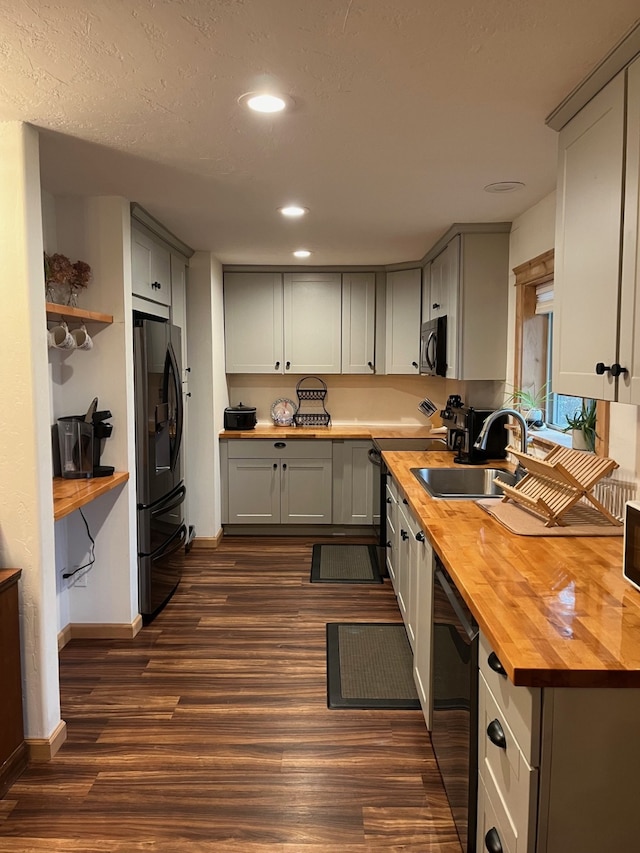 kitchen with wooden counters, stainless steel appliances, dark wood-type flooring, and sink