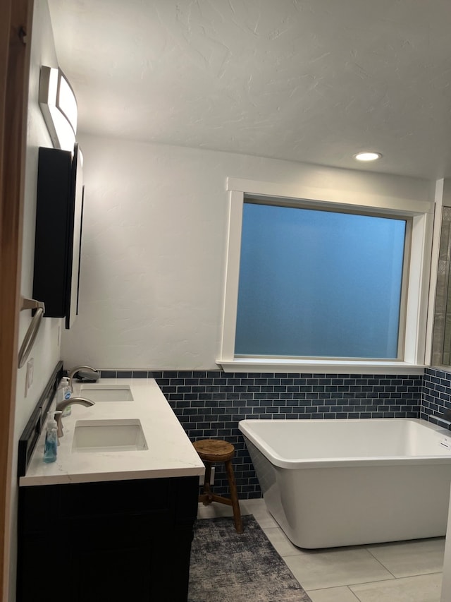 bathroom featuring tile patterned flooring, vanity, a tub to relax in, and tile walls