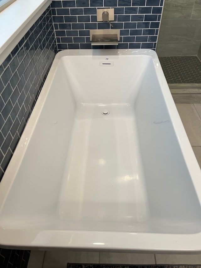 interior details with a shower, backsplash, and sink