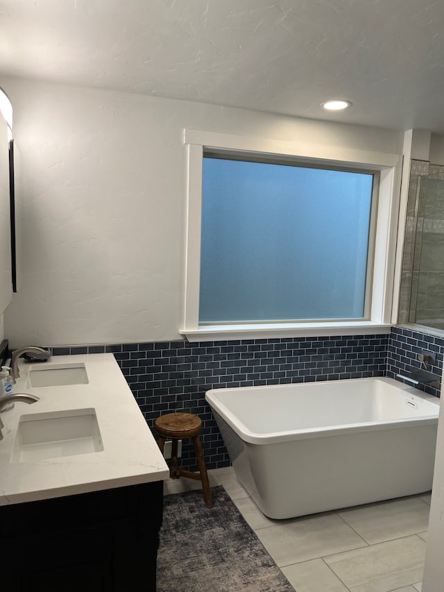 bathroom featuring tile patterned flooring, a bath, vanity, and tile walls