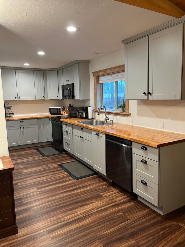 kitchen with sink, wood counters, dark hardwood / wood-style floors, gray cabinets, and appliances with stainless steel finishes