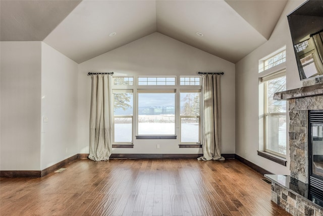 unfurnished living room with dark wood-style flooring, visible vents, a stone fireplace, high vaulted ceiling, and baseboards