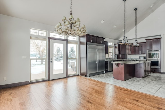 kitchen featuring stainless steel appliances, light countertops, light wood-type flooring, high vaulted ceiling, and a sink