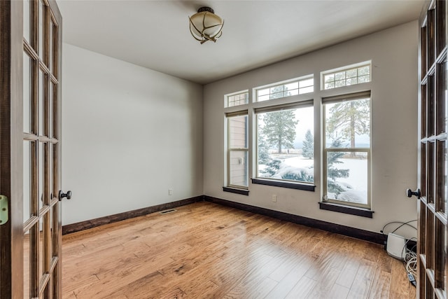 spare room featuring light wood-style flooring, visible vents, baseboards, and french doors