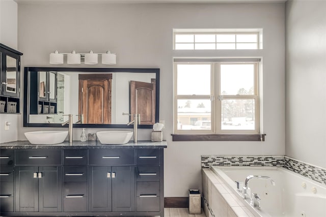 full bath with double vanity, a tub with jets, and a sink