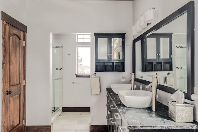 bathroom featuring double vanity, a shower stall, and baseboards