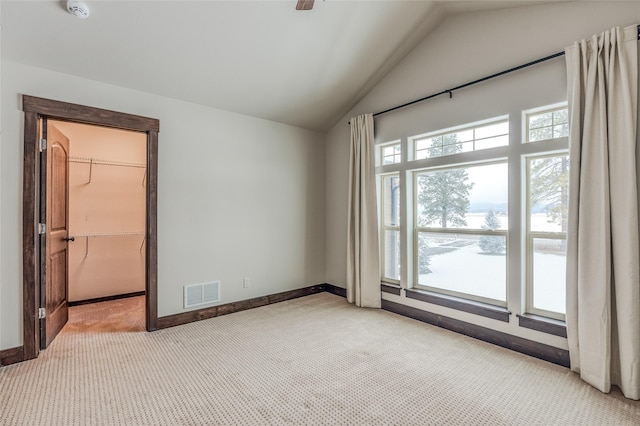 empty room with vaulted ceiling, carpet, visible vents, and baseboards