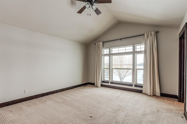 spare room with a ceiling fan, light carpet, vaulted ceiling, and baseboards