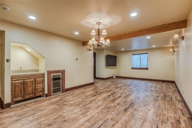 unfurnished living room with light wood finished floors, baseboards, beam ceiling, and recessed lighting