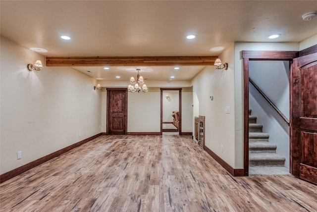 spare room with stairs, beamed ceiling, light wood-style flooring, and baseboards