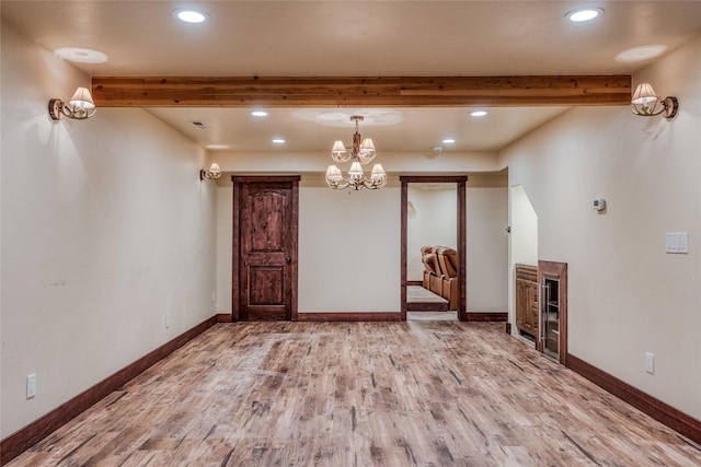 unfurnished room featuring baseboards, beamed ceiling, and wood finished floors