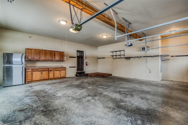 garage with a garage door opener and freestanding refrigerator