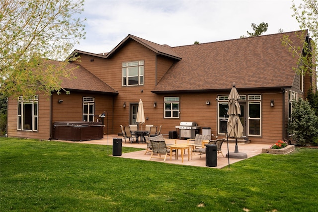 rear view of house featuring roof with shingles, a patio, a hot tub, and a lawn