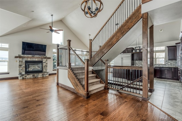 stairway featuring wood-type flooring, a fireplace, high vaulted ceiling, and baseboards