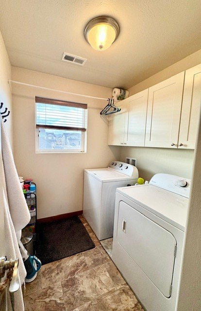 laundry room featuring separate washer and dryer and cabinets