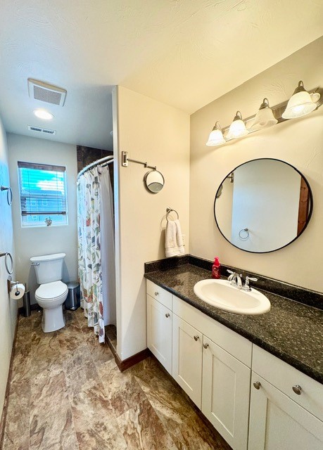 bathroom featuring a shower with shower curtain, vanity, and toilet