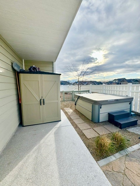 view of patio with a shed and a hot tub