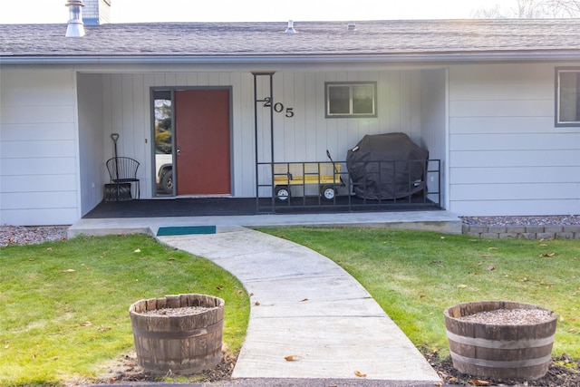 view of exterior entry featuring a yard and a porch