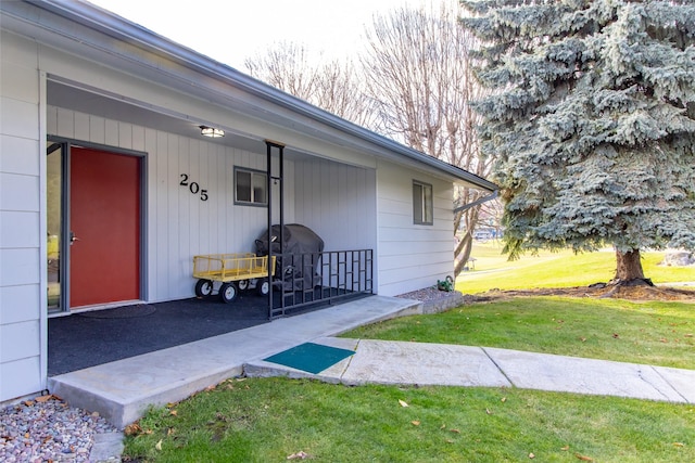 doorway to property featuring a lawn and a porch