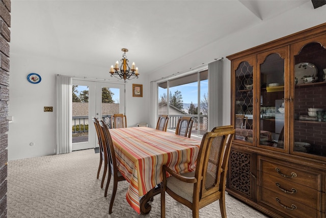 dining area featuring a chandelier, french doors, and light colored carpet