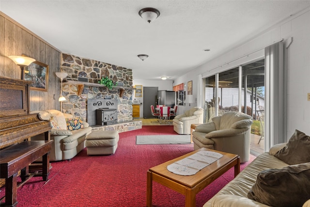 living room featuring a wood stove, wooden walls, and carpet