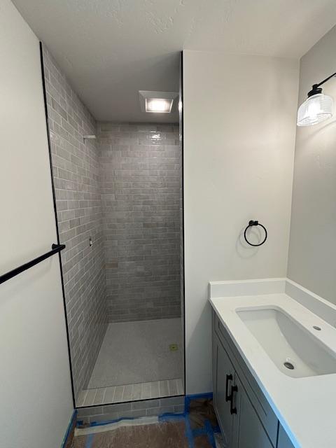 bathroom with vanity and a tile shower