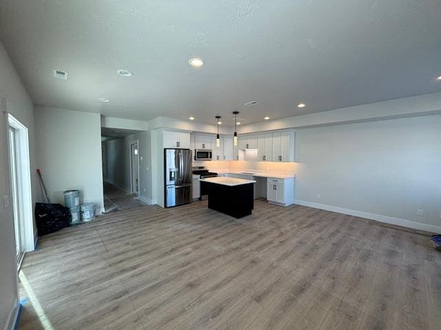 kitchen with appliances with stainless steel finishes, pendant lighting, white cabinetry, a center island, and light wood-type flooring