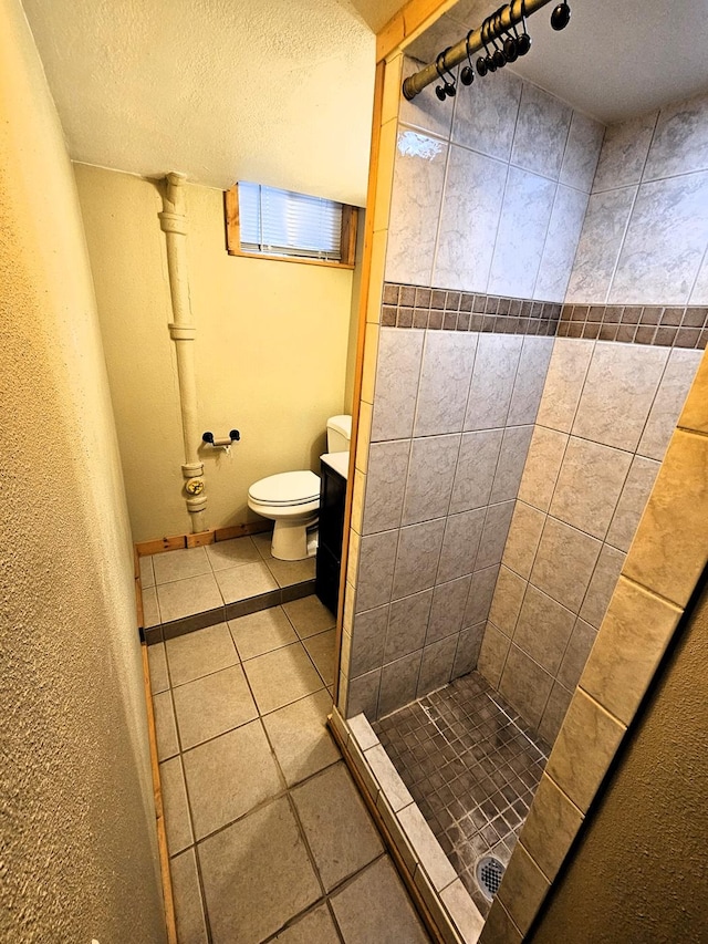 bathroom featuring vanity, toilet, a textured ceiling, and a tile shower