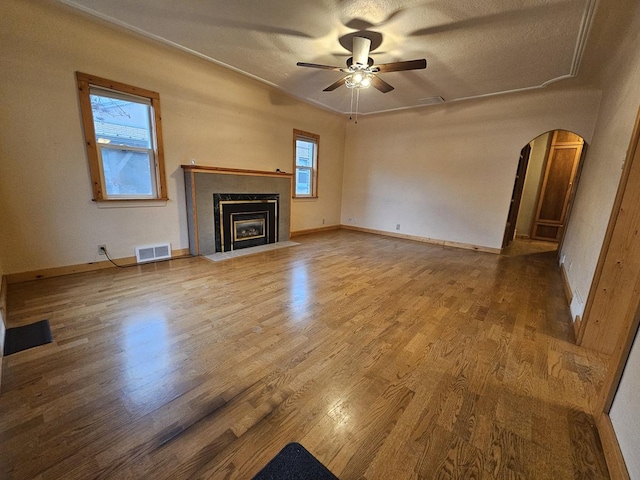 1733 S 11th St W, Missoula, MT 59801 - unfurnished living room with arched walkways, ceiling fan, wood finished floors, a fireplace with flush hearth, and baseboards