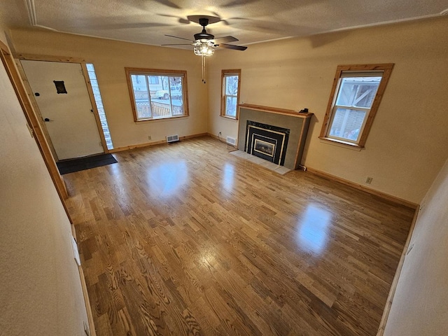 1733 S 11th St W, Missoula, MT 59801 - unfurnished living room featuring wood finished floors, a ceiling fan, baseboards, a fireplace with flush hearth, and a textured ceiling