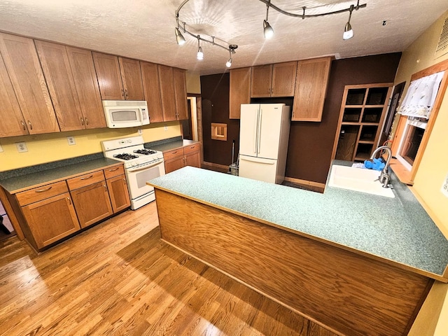 kitchen featuring white appliances, track lighting, sink, light hardwood / wood-style flooring, and a textured ceiling