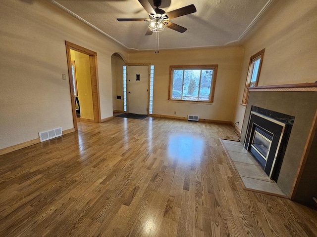 1733 S 11th St W, Missoula, MT 59801 - unfurnished living room with a tile fireplace, arched walkways, wood finished floors, a ceiling fan, and a textured ceiling