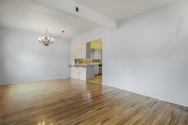 unfurnished living room with beam ceiling, wood-type flooring, sink, and an inviting chandelier