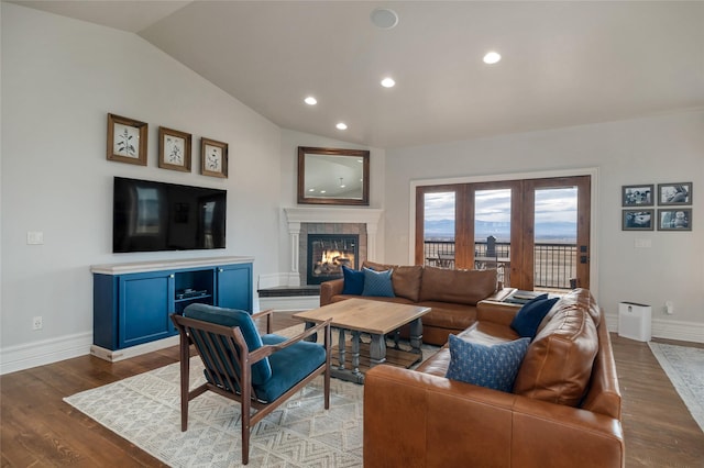 living room with hardwood / wood-style floors, a tiled fireplace, and vaulted ceiling