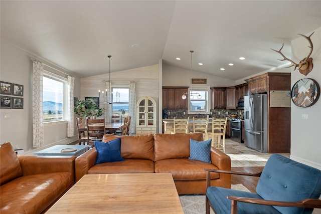 living room with a chandelier, light hardwood / wood-style floors, and vaulted ceiling