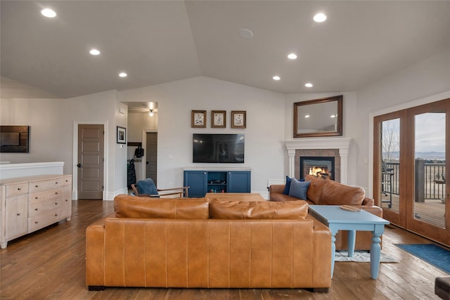 living room featuring hardwood / wood-style flooring, lofted ceiling, and a tile fireplace