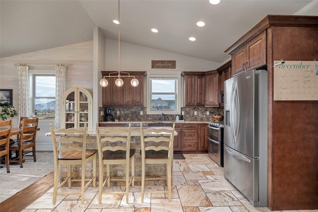 kitchen with a breakfast bar, a center island, stainless steel appliances, and lofted ceiling