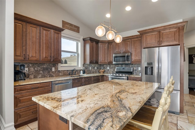 kitchen featuring appliances with stainless steel finishes, vaulted ceiling, pendant lighting, a center island, and a breakfast bar area