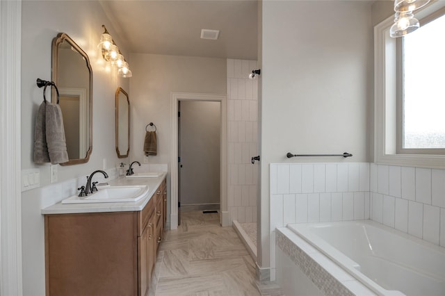 bathroom featuring tiled bath and vanity