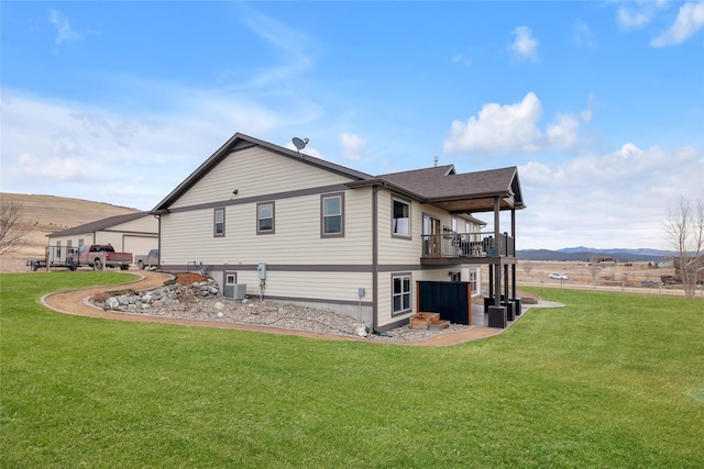view of side of property featuring a balcony, a yard, central AC unit, and a mountain view