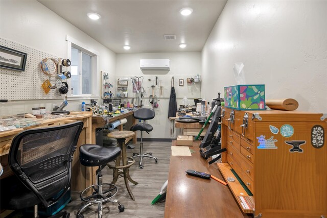 office space featuring a workshop area, a wall mounted AC, and light hardwood / wood-style flooring