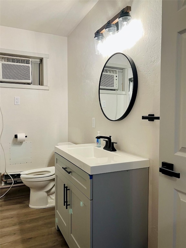 bathroom featuring hardwood / wood-style floors, vanity, toilet, and a wall mounted AC