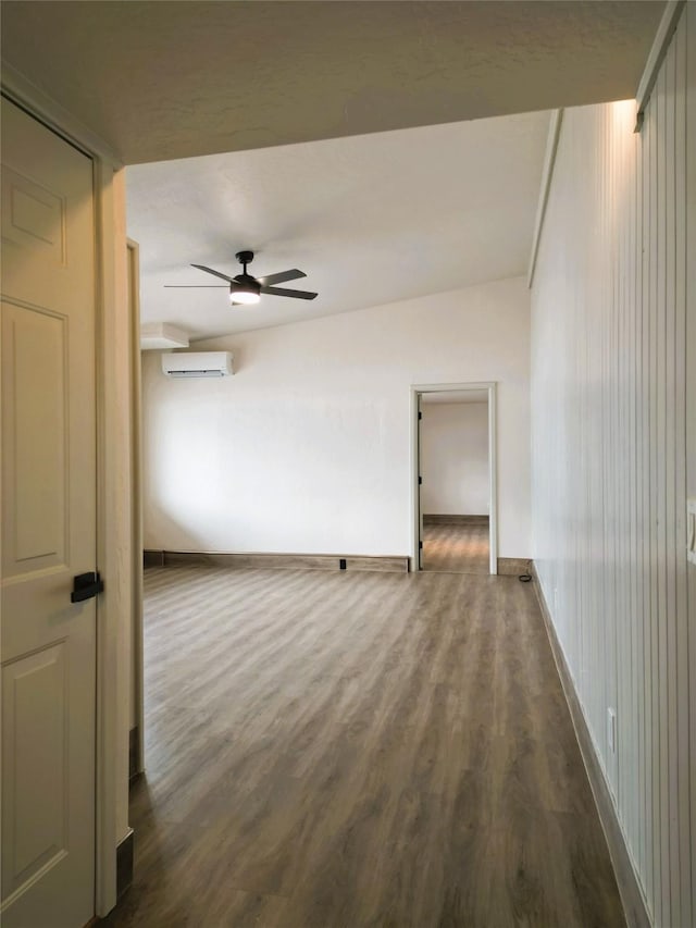 spare room with a wall unit AC, ceiling fan, and wood-type flooring