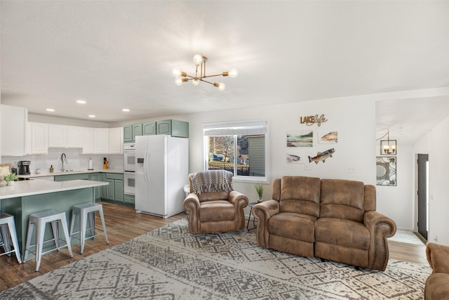 living room featuring light hardwood / wood-style flooring, a notable chandelier, and sink