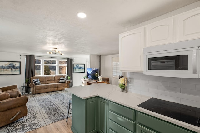 kitchen featuring black electric cooktop, a notable chandelier, light hardwood / wood-style floors, white cabinetry, and green cabinets