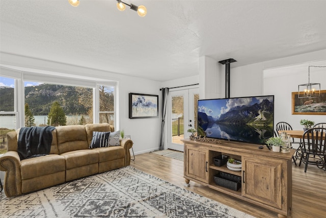 living room with a wood stove, a chandelier, a textured ceiling, and light wood-type flooring